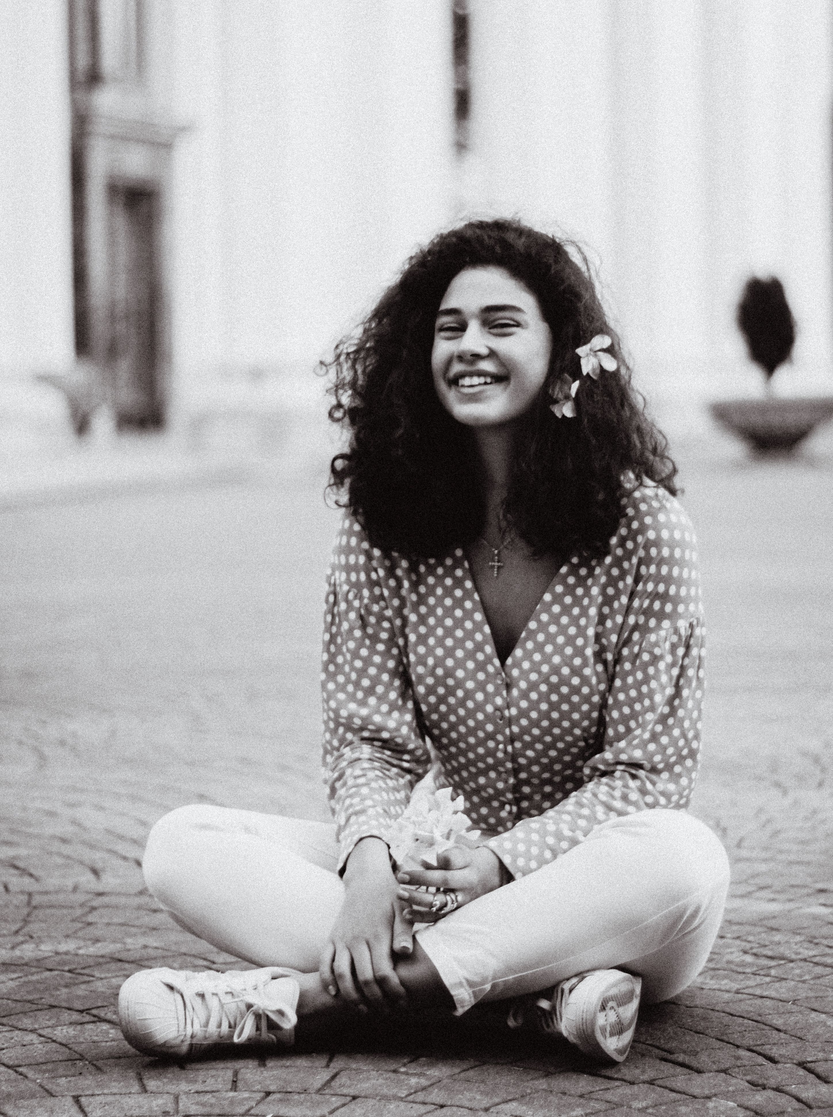 Smiling Woman Sitting Outdoors in Monochrome · Free Stock Photo