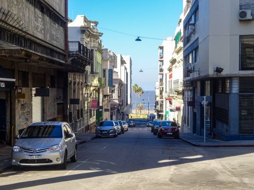 Free Peaceful city street with parked cars leading to a scenic waterfront view. Stock Photo