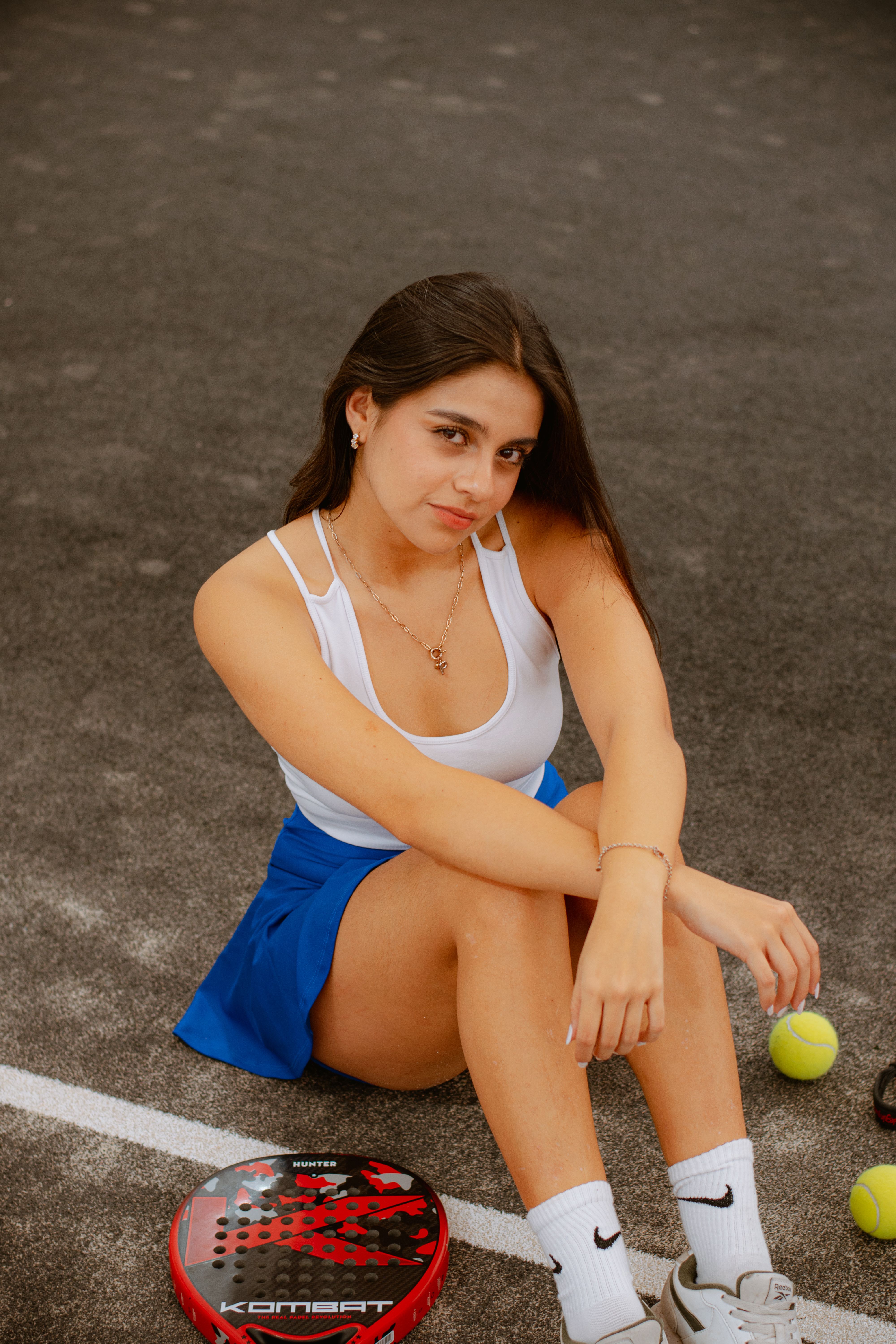 Young woman sitting on padel court with racket and balls, Puebla, Mexico.
