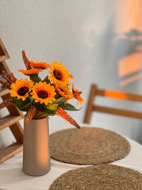 Free Vibrant sunflowers in a vase with warm sunlight on a table setting. Stock Photo