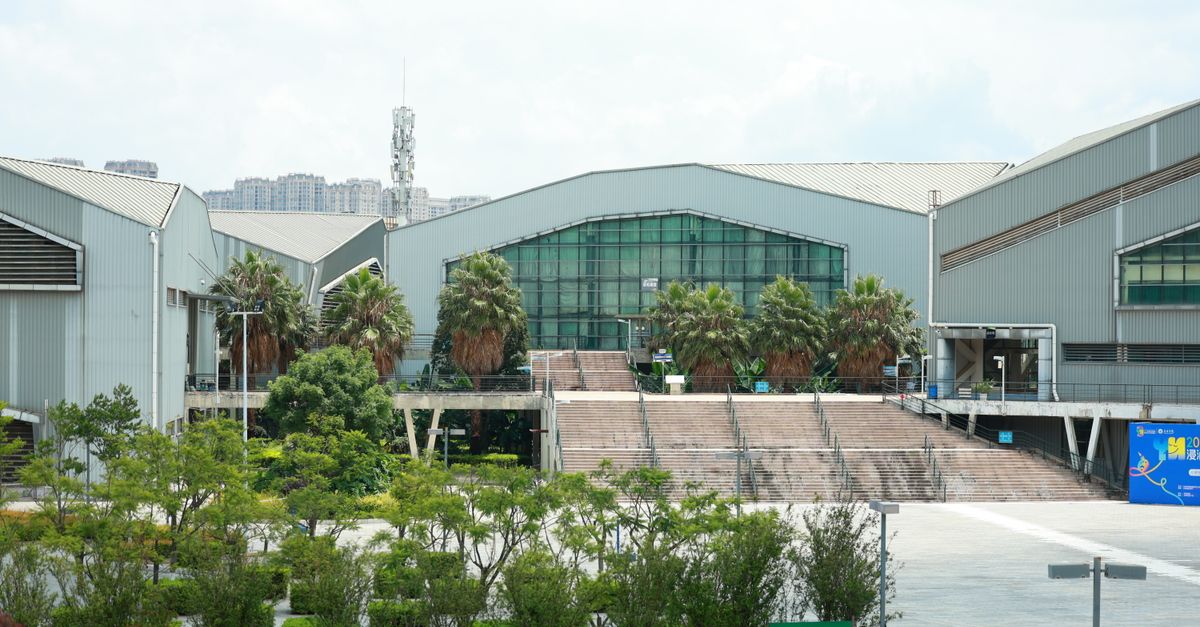 Exterior view of an industrial building surrounded by lush greenery on a sunny day.