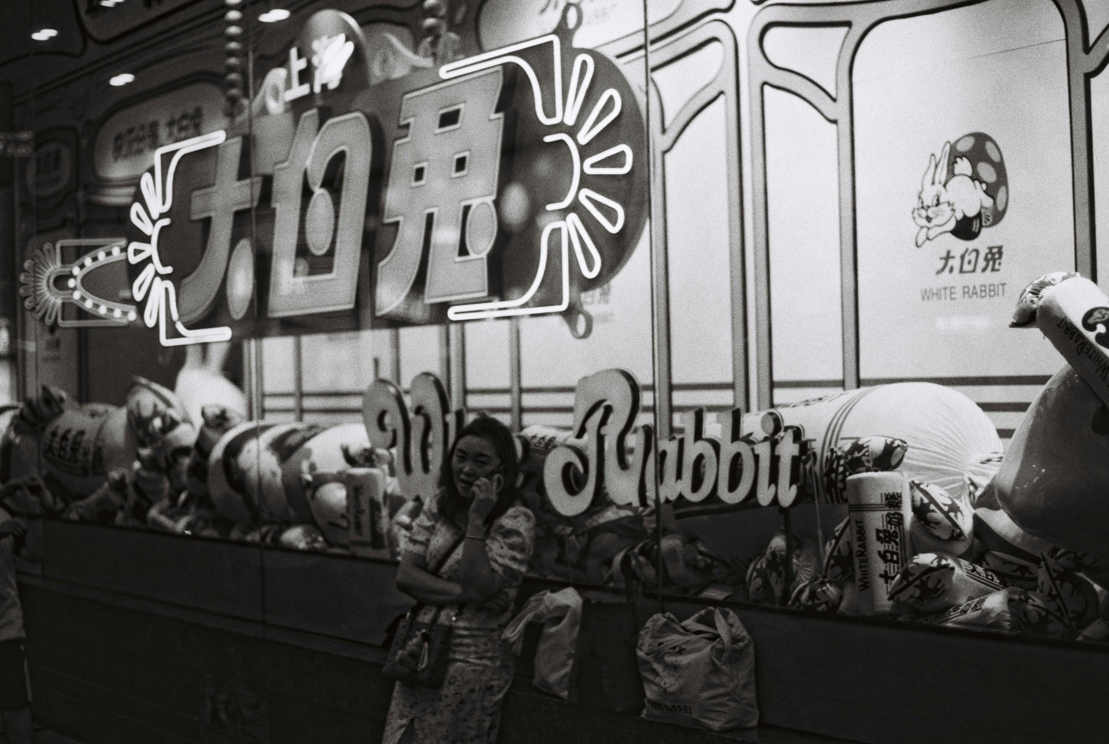 Gratis Monokromt foto af en kvinde nær en vintage slikbutik med hvid kanin i Shanghai. Lagerfoto