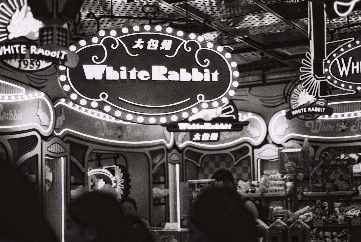 Vintage-themed candy store featuring White Rabbit brand signage in a busy market setting.