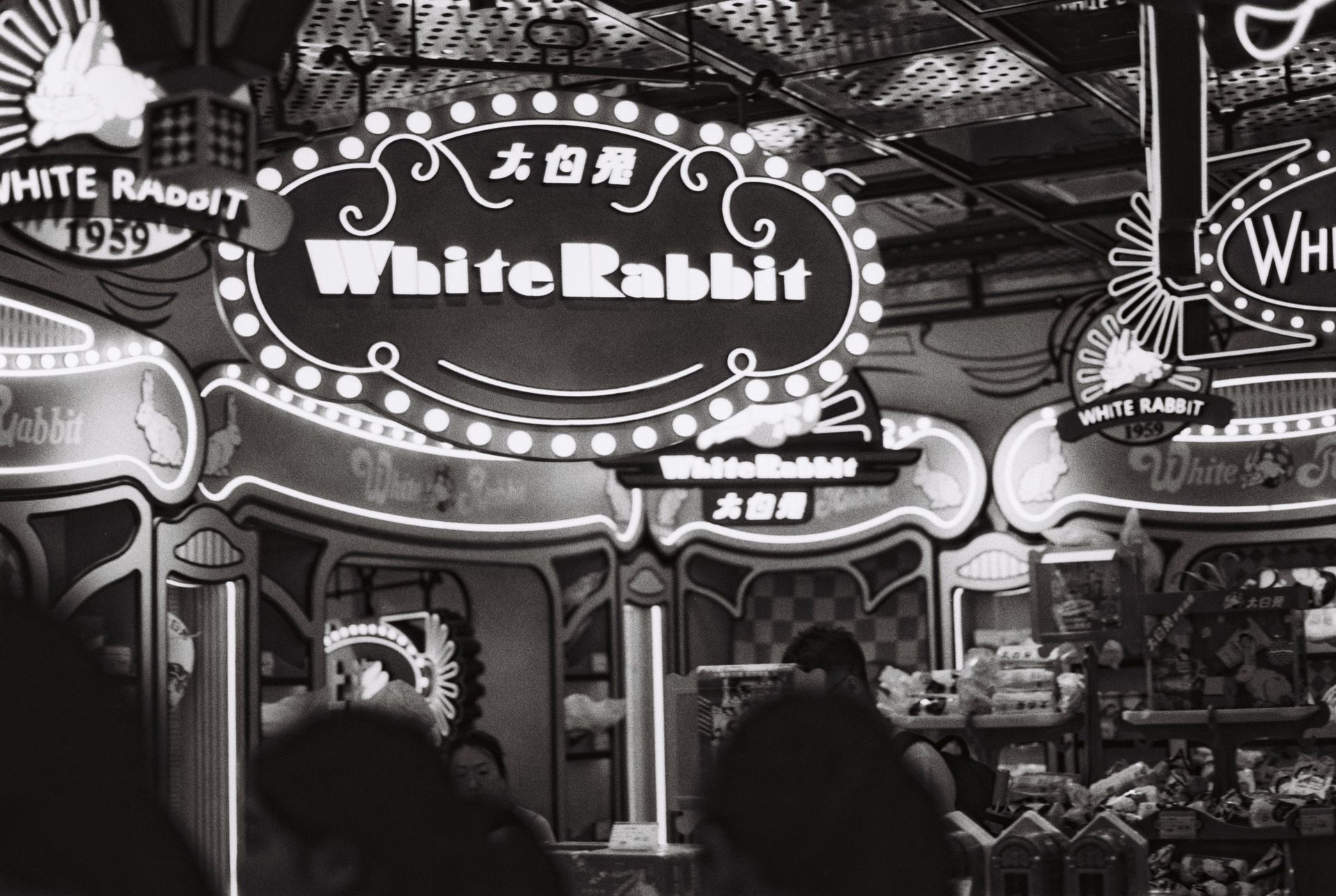 Vintage-themed candy store featuring White Rabbit brand signage in a busy market setting.