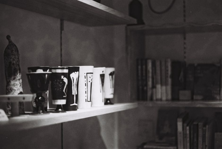 Monochrome shelves displaying unique decorative cups and books, offering an artistic vibe.