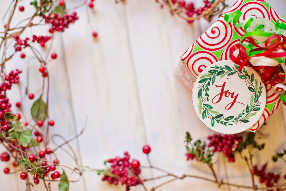 christmas stocking tags - A colorful wrapped Christmas gift with a 'Joy' tag surrounded by festive red berries.