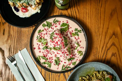 Free Aerial view of colorful gourmet dishes on a wooden table, featuring vibrant sauces and fresh greens. Stock Photo