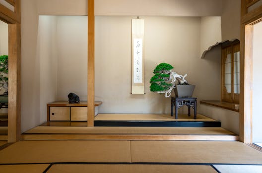 A serene Japanese room features a bonsai tree and calligraphy scroll, showcasing Zen aesthetics and calm ambiance.