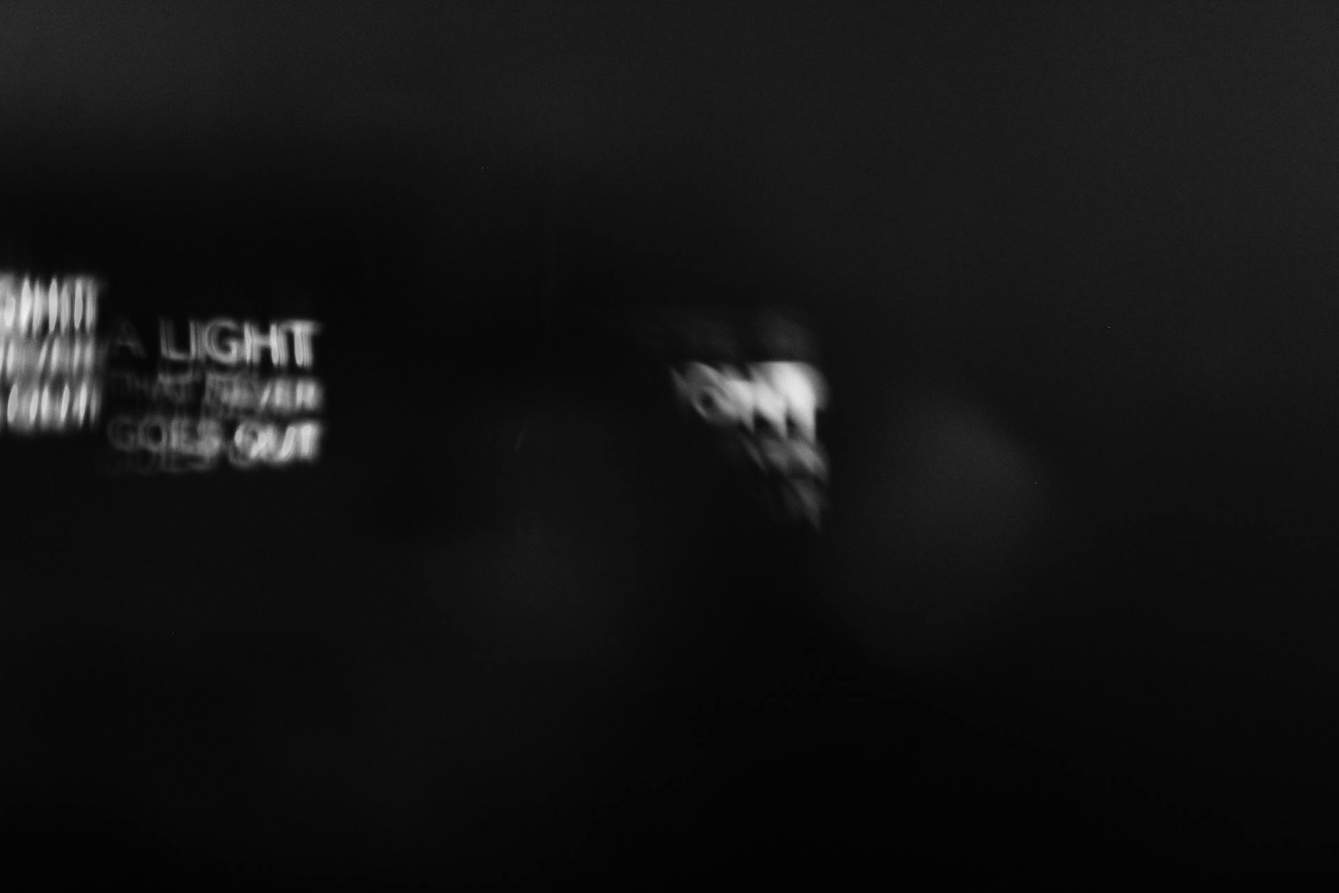 Blurred white text with light effects on a black background, creating an abstract feel.