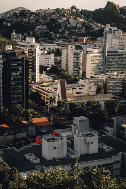 Free A scenic aerial view of a cityscape featuring modern high-rise buildings and lush hills in the background. Stock Photo