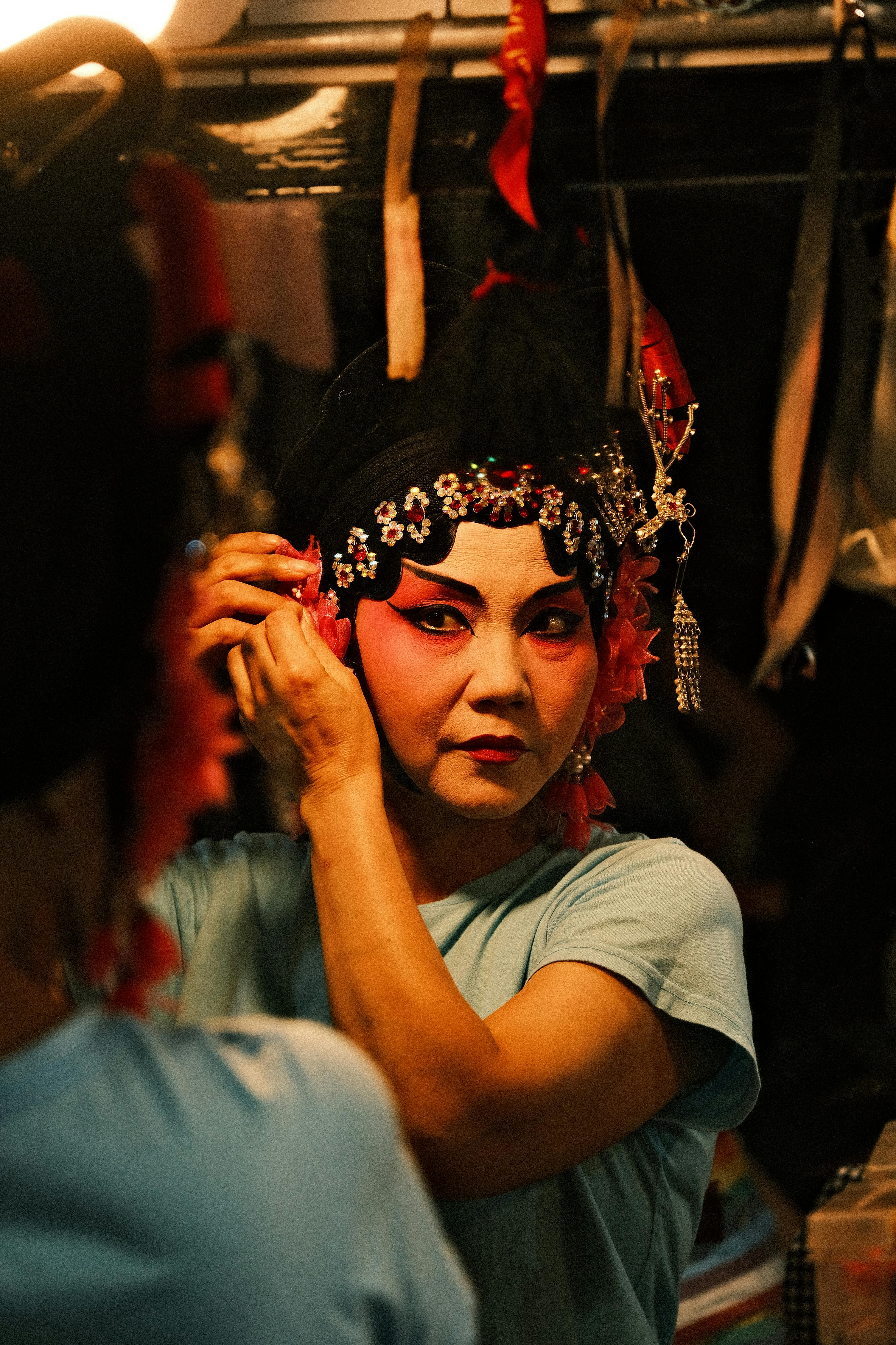 Free An actress applies makeup and adjusts her costume for a Chinese opera performance. Stock Photo