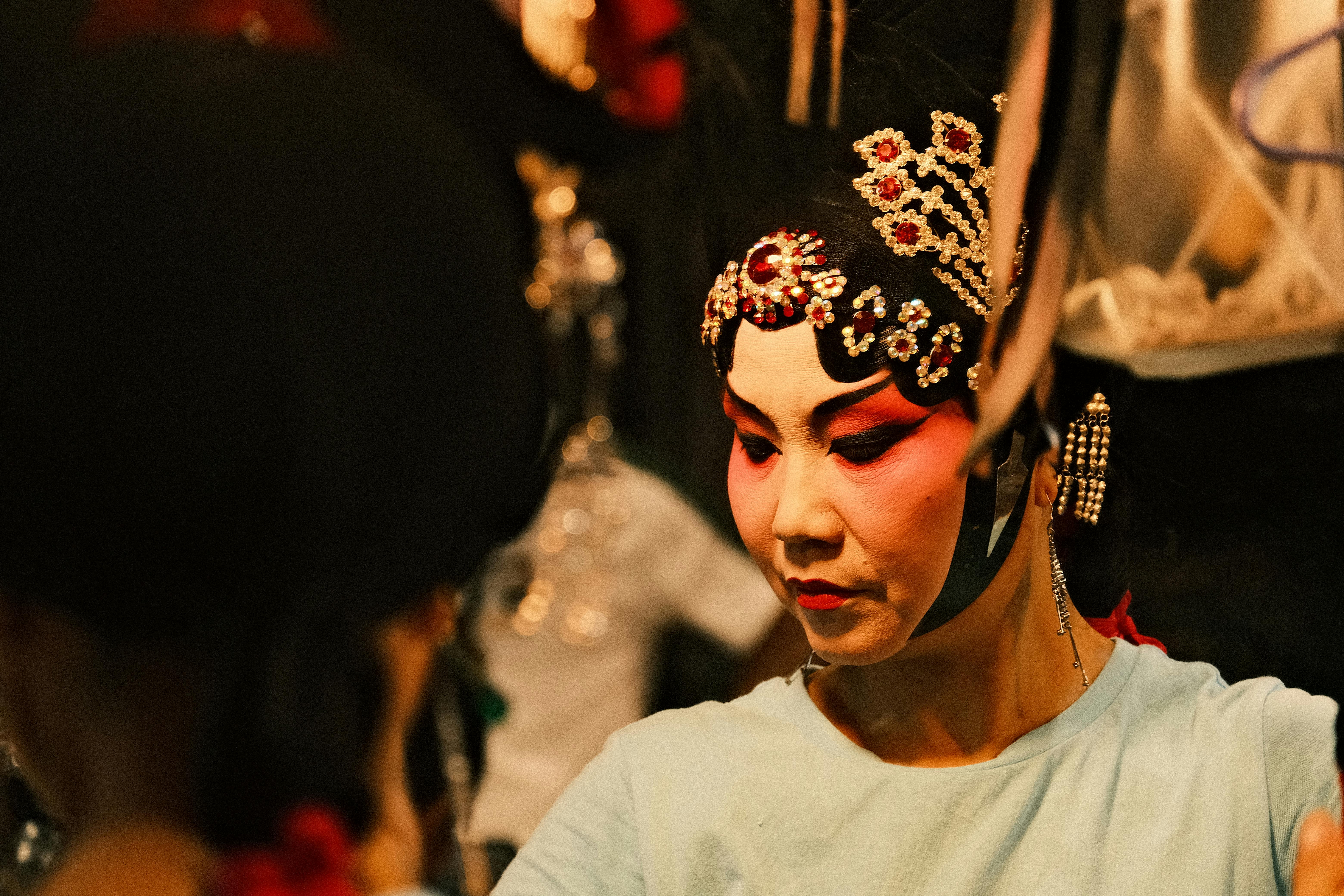 Free A focused Chinese opera artist in traditional makeup and costume preparing backstage. Stock Photo
