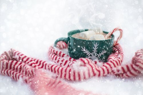 Free A steaming cup of hot chocolate with marshmallows and candy cane in a snowy setting, perfect for winter coziness. Stock Photo