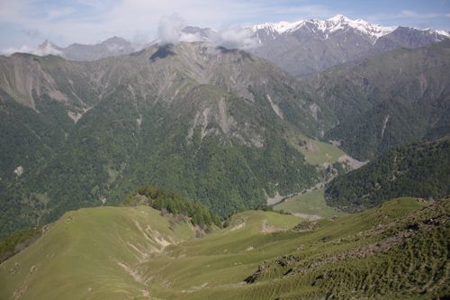 Free Breathtaking view of lush green valleys and snow-capped mountains under a clear sky. Stock Photo