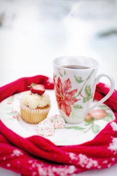 优雅的花卉马克杯，铺在节日红布上，搭配茶和纸杯蛋糕，非常适合节日聚会