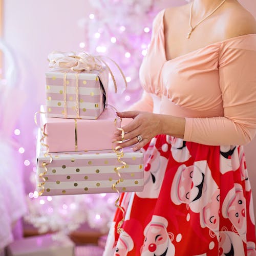 Free Woman Wearing Pink V-neck Long-sleeved Shirt and Red Skirt Holding Christmas Gifts Stock Photo