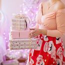 室内，身着节日服装的妇女拿着包装精美的圣诞礼物
