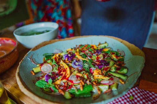 Vibrant fresh salad topped with edible flowers and vegetables on a rustic plate.