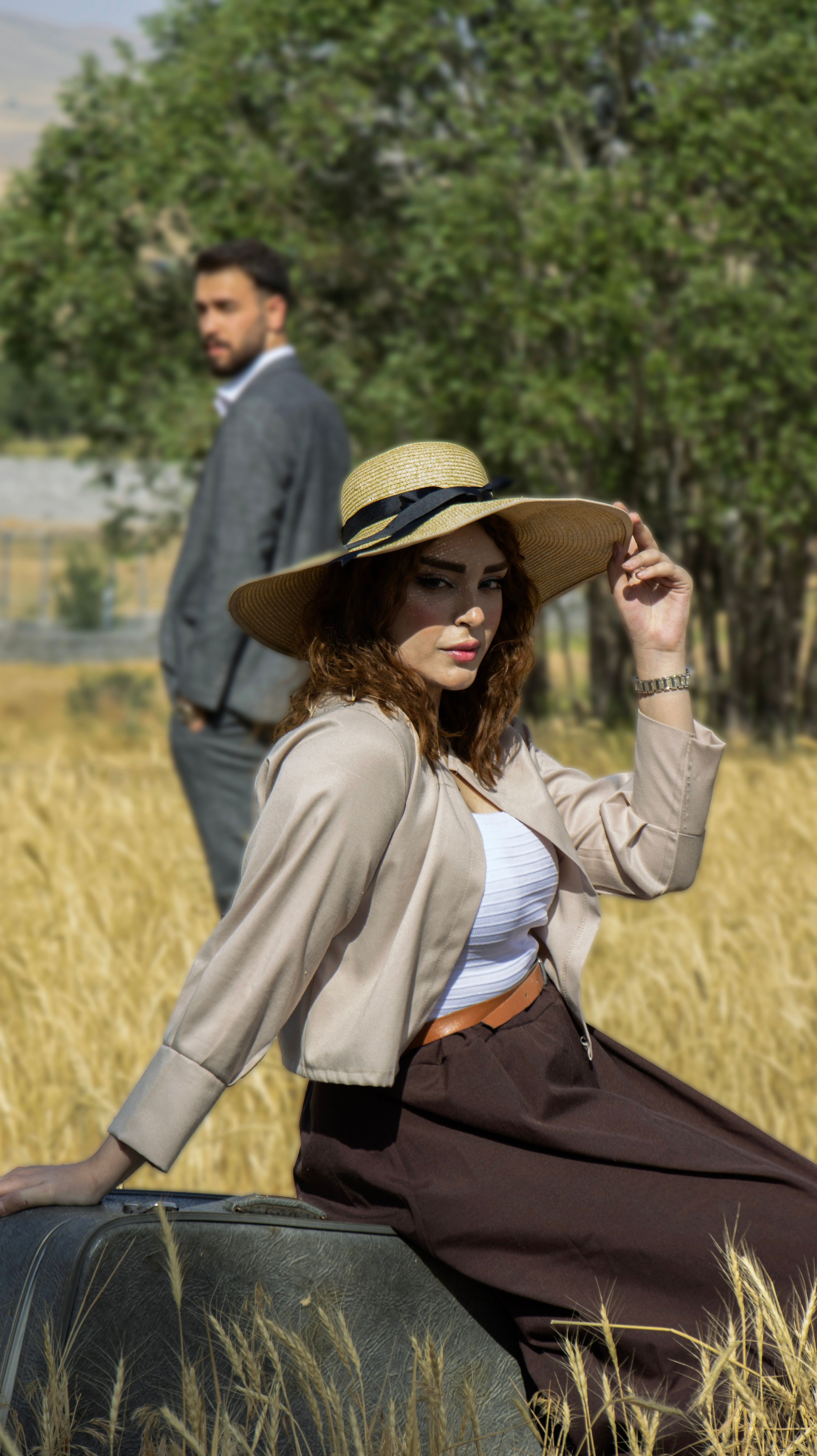 A fashionable couple in a field wearing summer attire with a vintage vibe. Perfect for lifestyle themes.