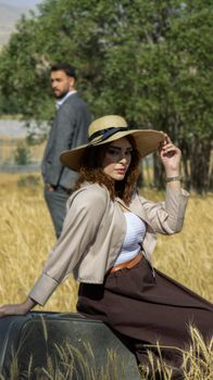 A fashionable couple in a field wearing summer attire with a vintage vibe. Perfect for lifestyle themes.