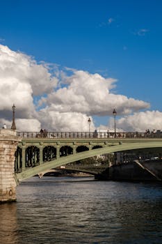 A vibrant scene of a historic Parisian bridge under a blue sky, ideal for travel and architecture themes.