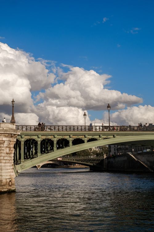 Free A vibrant scene of a historic Parisian bridge under a blue sky, ideal for travel and architecture themes. Stock Photo