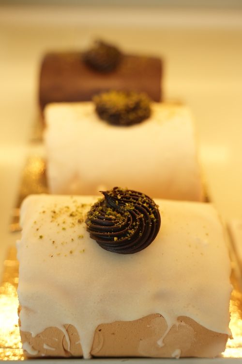 Free Assorted frosted cakes topped with chocolate and pistachio in a bakery. Stock Photo