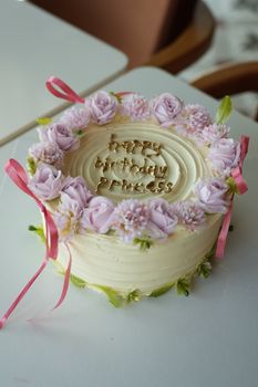 Elegant birthday cake adorned with pink roses and ribbons, perfect for celebrations.