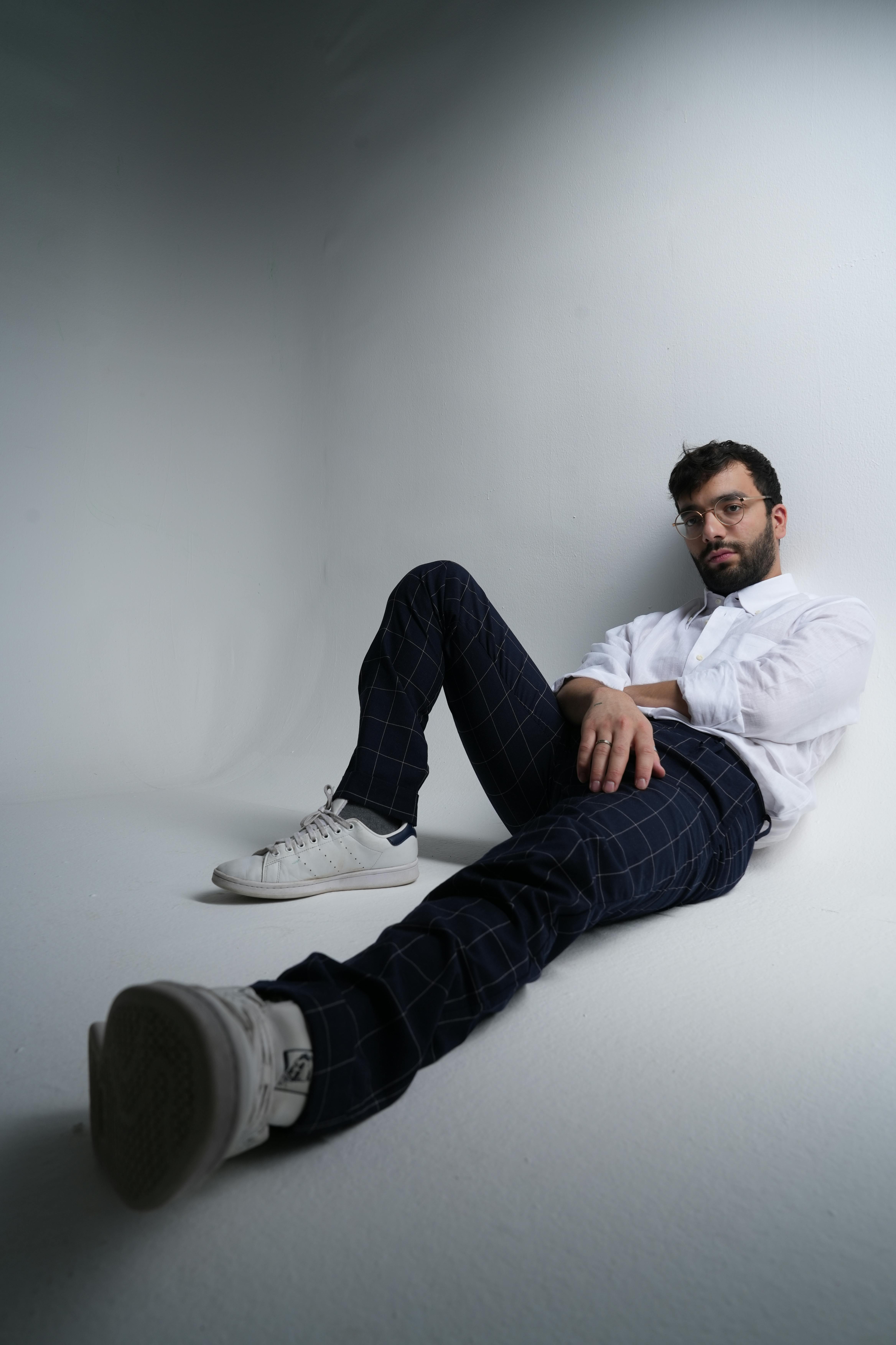 Stylish man in a white shirt and plaid pants posing in a modern studio.
