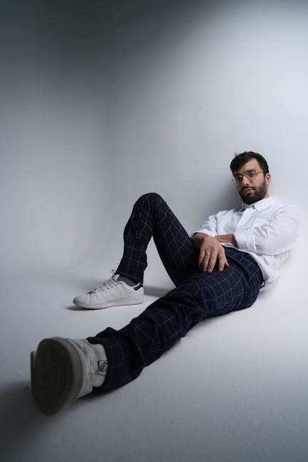 Stylish man in a white shirt and plaid pants posing in a modern studio.