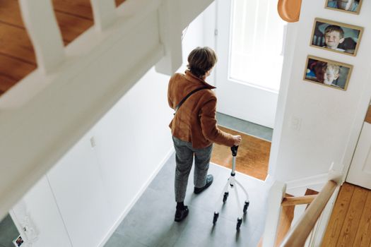 A senior adult walking indoors with a rollator, depicting independence and mobility