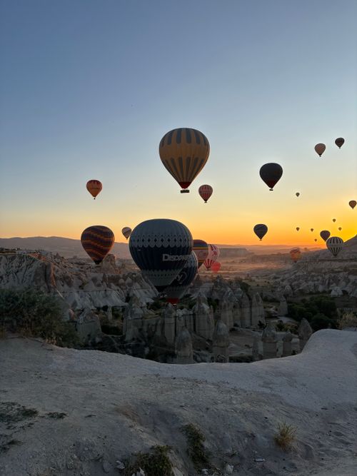 Free Colorful hot air balloons soar over Cappadocia's rocky landscape at sunrise. Stock Photo