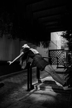 Black and white photo of a woman in a denim skirt striking a pose outdoors.