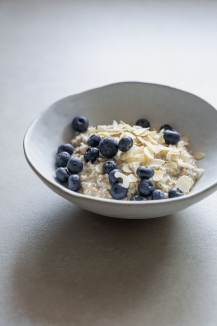 Bowl of oatmeal topped with fresh blueberries and almond slices for a healthy breakfast.