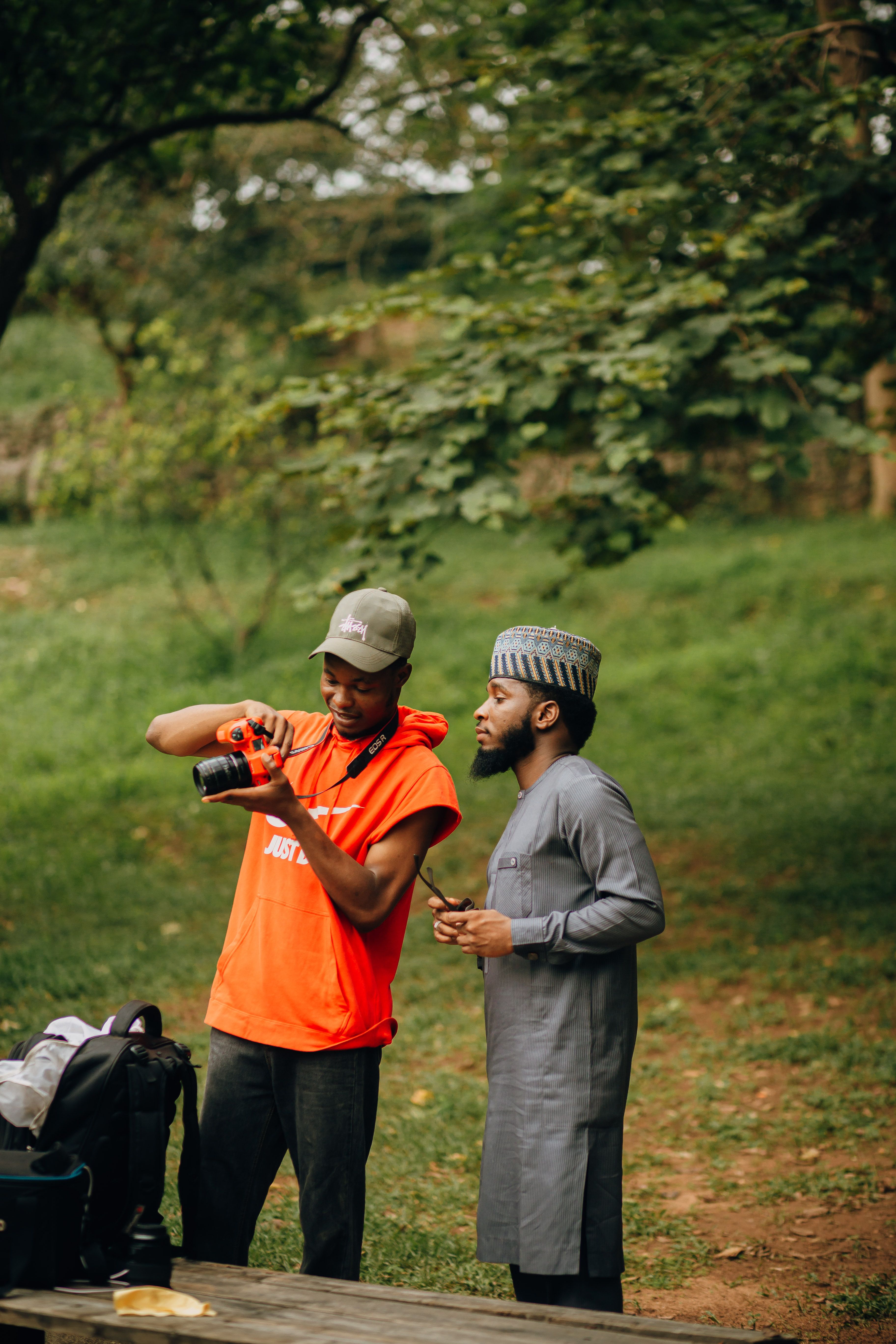 Two men evaluating camera photos outdoors, showcasing casual collaboration.
