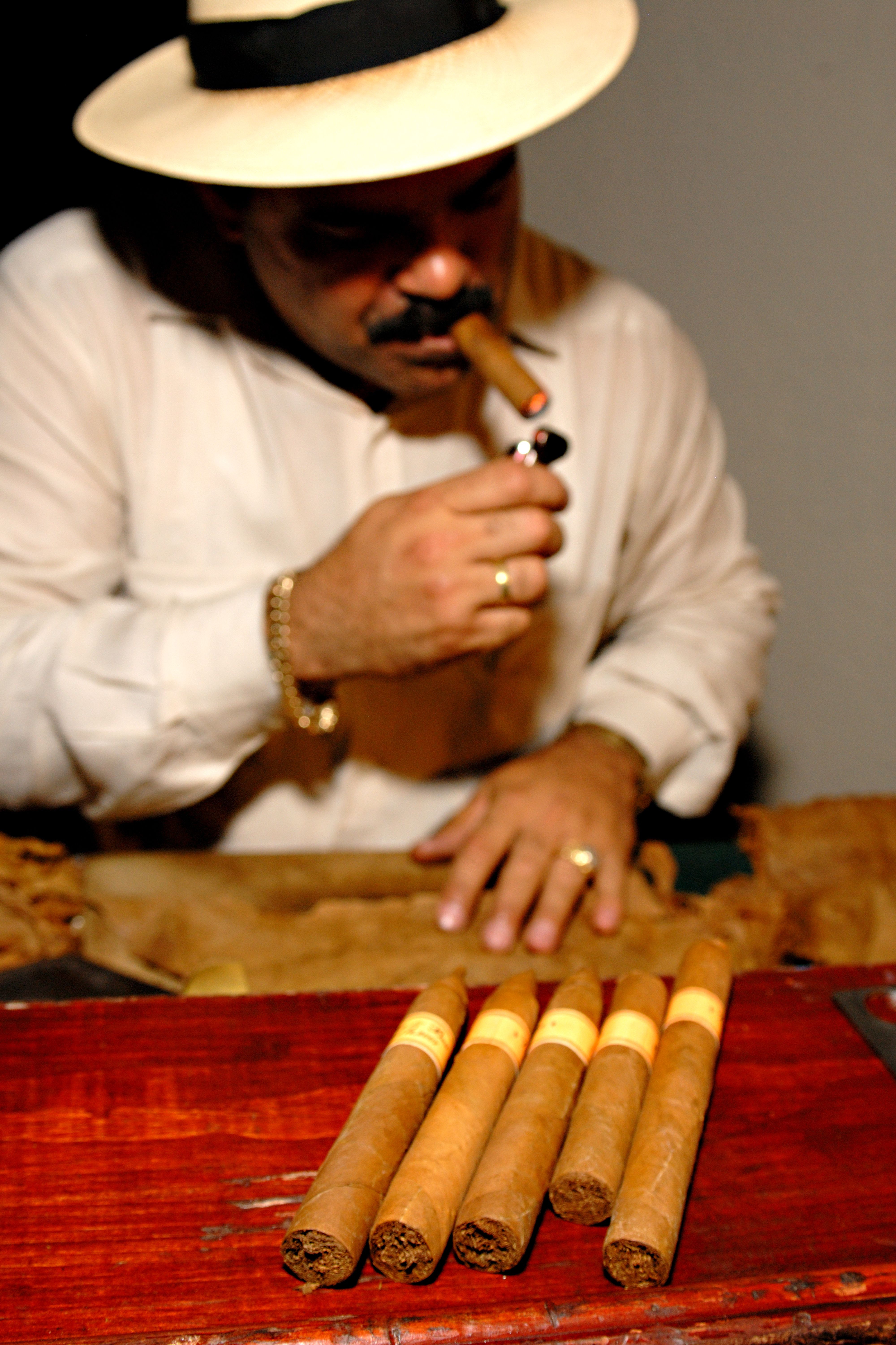 Man in Cuba with cigars on table, showcasing traditional craftsmanship.