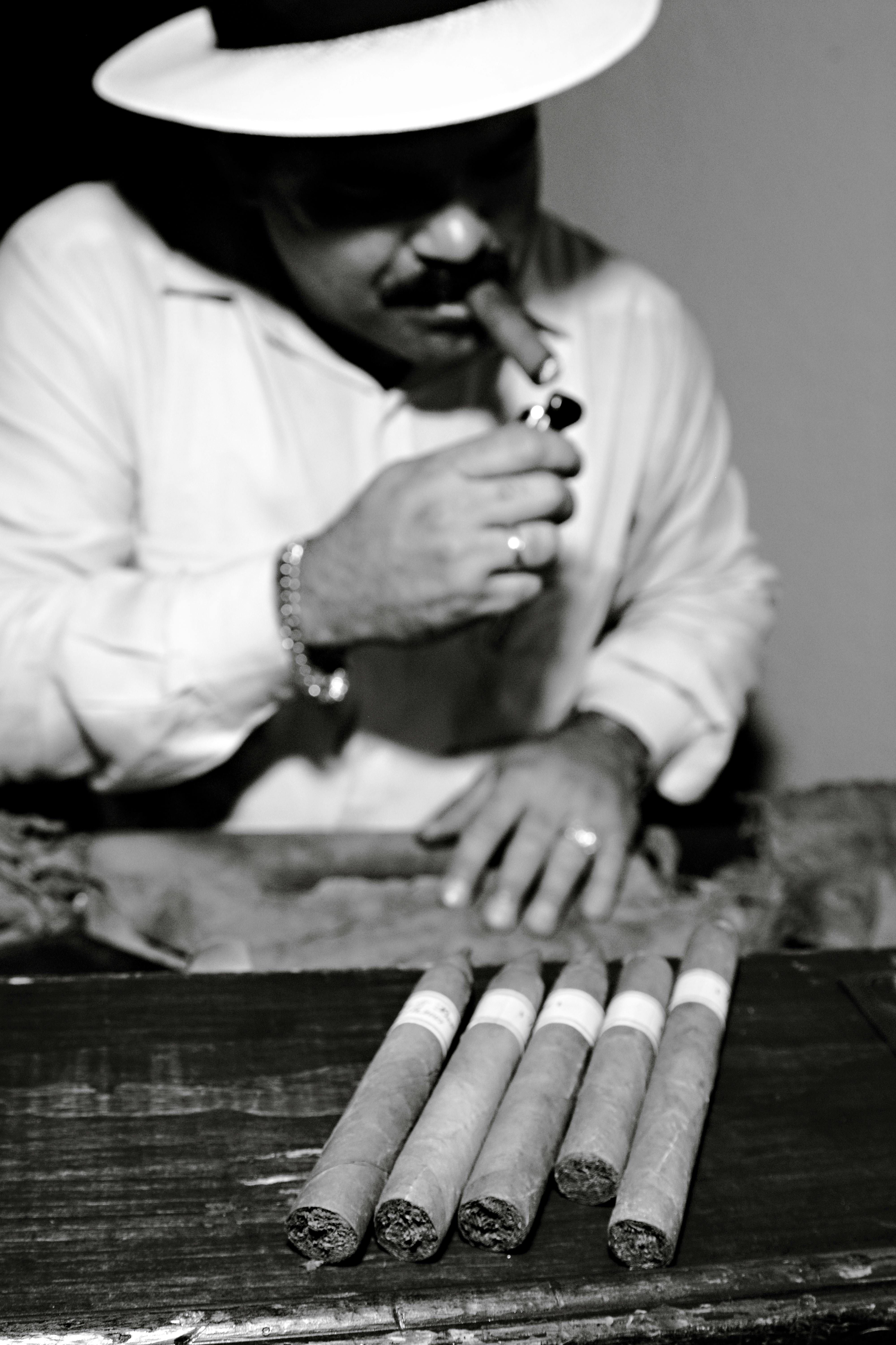 Black and white image of a Cuban artisan rolling cigars, highlighting traditional craftsmanship.