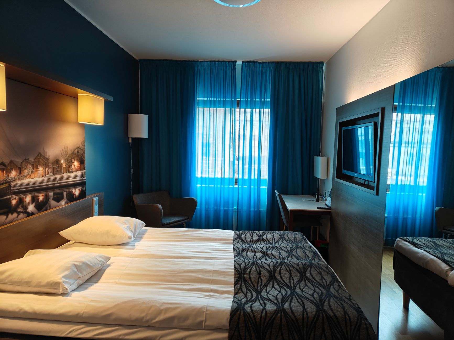 保留採光又要隱私?先評估空間需求最關鍵 A stylish hotel room with blue curtains and modern decor, perfect for relaxation.