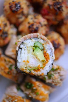Colorful sushi roll featuring fresh avocado, rice, and seafood displayed in an artistic close-up.