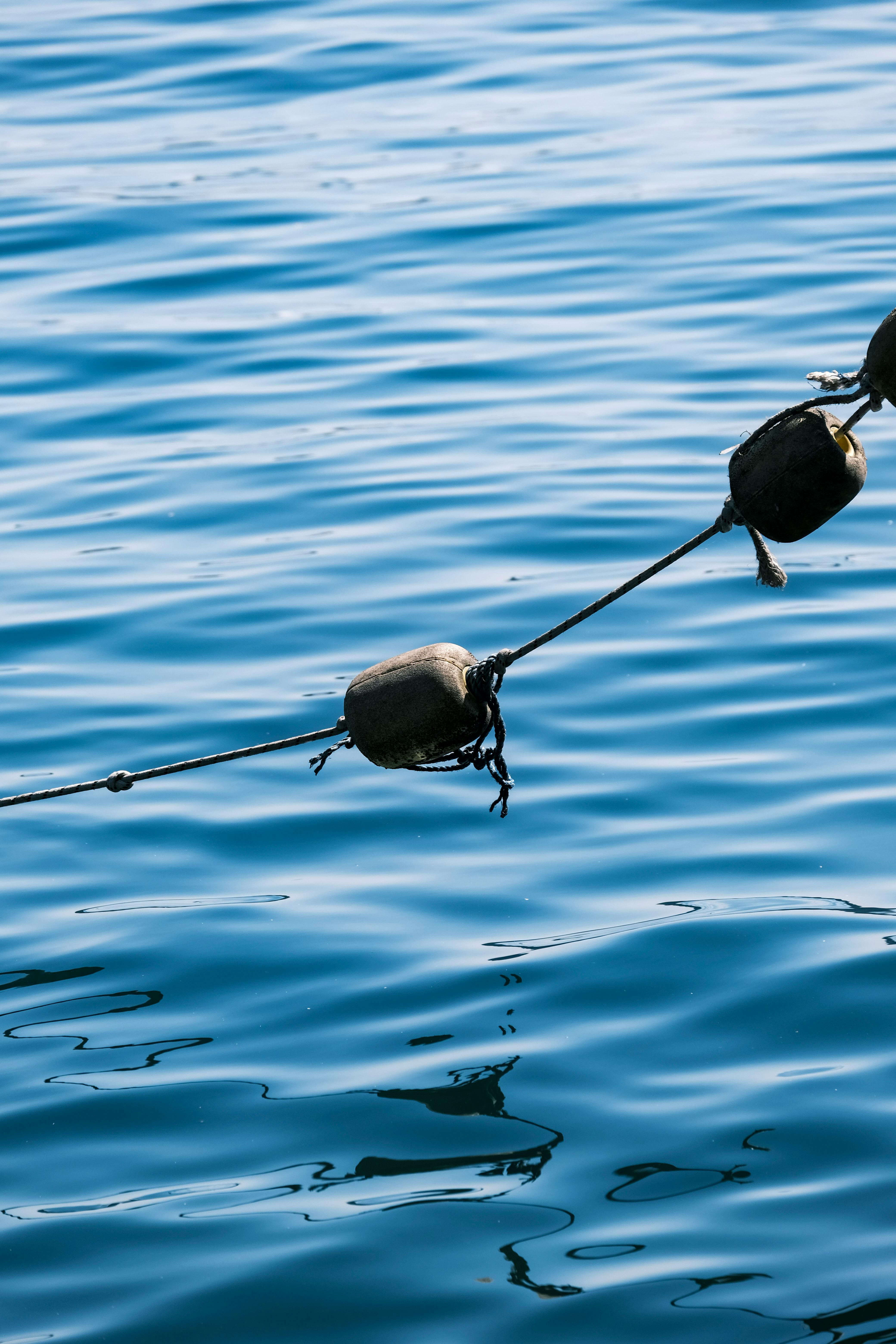 Calm blue sea with floating buoys reflecting sunlight, peaceful ocean scene.