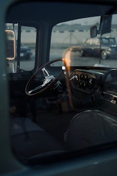 Vintage car interior with a focus on steering wheel and dashboard, seen through the window.
