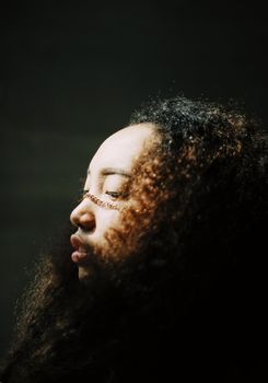 在艺术灯光的工作室环境中，拍摄了一位卷发女性的侧面肖像