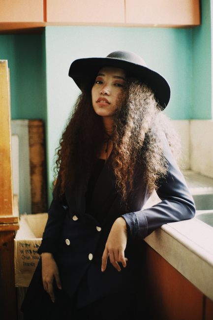 Portrait of a fashionable woman wearing a hat and blazer, exuding vintage charm indoors.