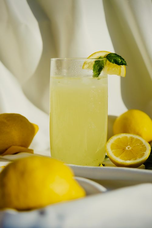 Free Cool glass of lemonade with lemons and mint garnish, perfect thirst-quencher. Stock Photo