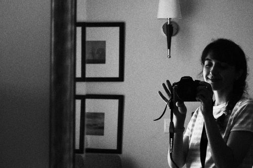 Free A black and white image of a woman taking a mirror selfie indoors, creating a classic and artistic feel. Stock Photo