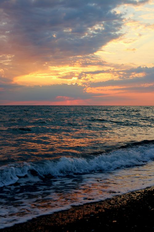 Free Serene sunset with vibrant colors over gentle ocean waves, capturing a tranquil evening atmosphere. Stock Photo