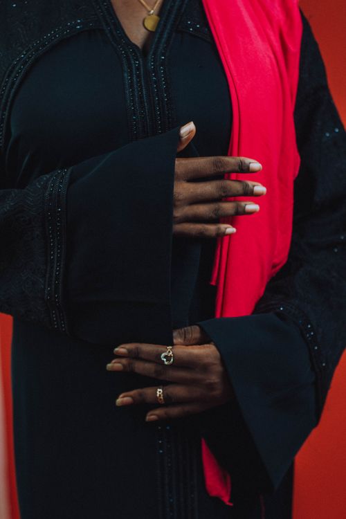 Free Close-up of woman in black abaya and red scarf, hands adorned with rings. Stock Photo