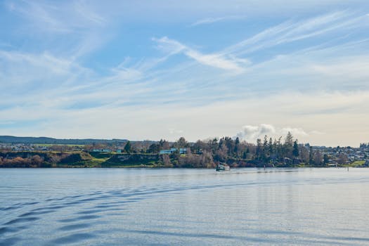 Tranquil view of Lake Taupō with a boat and distant shoreline under a bright blue sky.