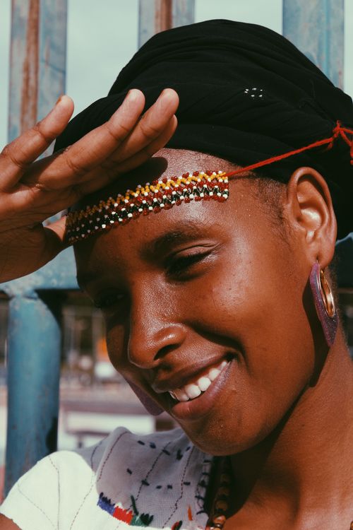 Free A cheerful woman outdoors, wearing beaded headwear and a bright smile, enjoying the sunny day. Stock Photo