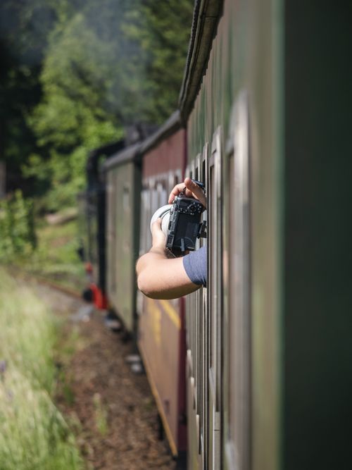 Free A person capturing the landscape while leaning out the window of a moving train in Zittau, Germany. Stock Photo